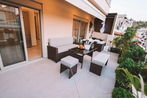 A balcony with wicker furniture, a table with fruits, and potted plants.