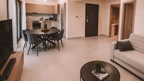 Een moderne woonkamer met een bank, een eettafel met stoelen, een salontafel en een tv op een dressoir.