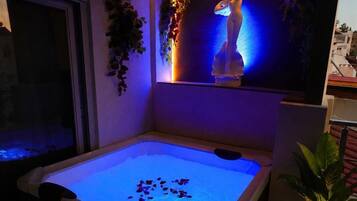 Un espace spa comprenant une piscine chauffée, une statue et des plantes en pot.