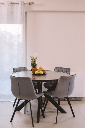 A dining area with a round table, four grey chairs, and a fruit bowl on the table. - Luxury Apartment and wirlpool over athen/Kesariani (Kesariani)