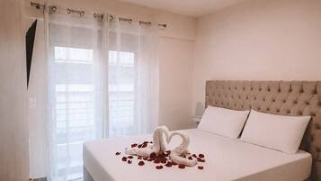 Ein Hotelzimmer mit einem großen Bett, einem gepolsterten Kopfteil und einem dekorativen Schwan aus Rosenblättern auf dem Bett.