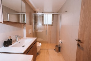 A modern bathroom with a glass-enclosed shower, a white sink, and a toilet. - Luxury Apartment and wirlpool over athen/Kesariani (Kesariani)