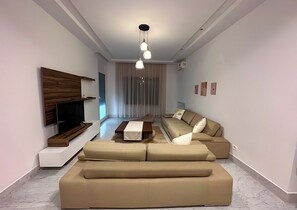 Ein modernes Wohnzimmer mit einer Eckcouch, einem Flachbildfernseher und einem Essbereich.