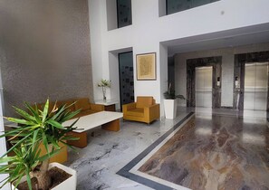 Eine moderne Lobby mit Marmorboden, einer Rezeption und einer Sitzecke mit Blumentopf.