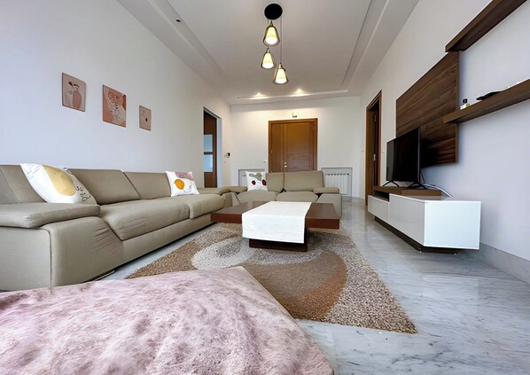 Una sala moderna con sofá, mesa de centro y televisor sobre un mueble.