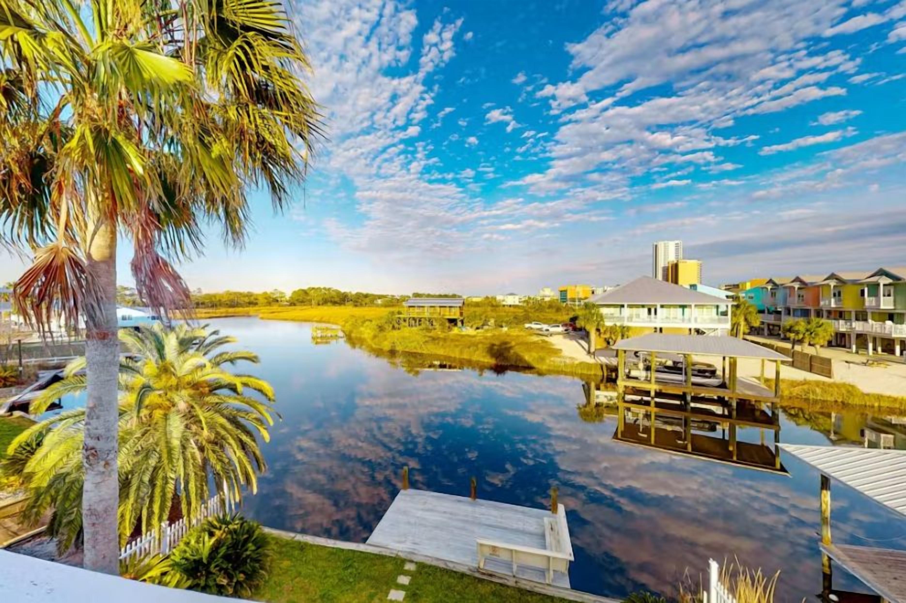 A waterfront property with a dock, a body of water, and buildings in the background.
