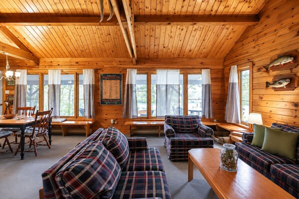 A cabin interior with a dining area, a sofa set, and a fish mounted on the wall.