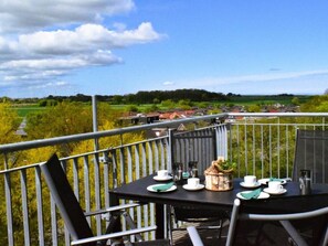 A balcony with a table set for two, overlooking a rural landscape with houses and greenery. - 48.5.s Waterkant (Wangerland)