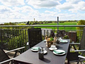 An outdoor dining area with a table set for two, overlooking a green field and a distant building. - 48.5.s Waterkant (Wangerland)