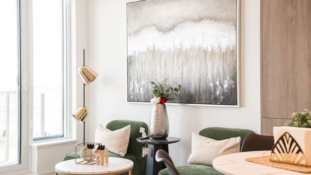 Uma sala de estar moderna com um sofá verde, uma mesa de centro redonda e um quadro minimalista na parede.