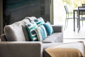 Ein graues Sofa mit gemusterten Kissen und einer beigen Decke.