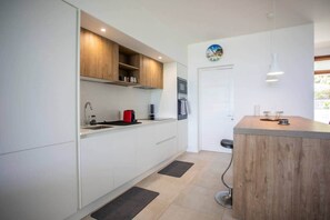 A modern kitchen with white cabinetry, a wooden countertop, and a built-in oven. - Sunset and Sea Views - Two Bed Apt Central Tamarin (Black River)