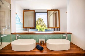 Un bagno con due lavandini, una doccia e un'ampia finestra vista verde.