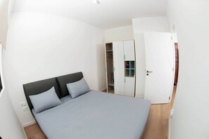 Ein Zimmer mit einem Bett, einem Kleiderschrank und einer Tür.