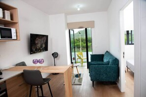 Ein moderner Wohnraum mit Essbereich, einer Couch und Blick durch eine Glastür.