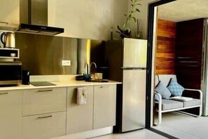 Eine moderne Küche mit Einbauofen, Spüle und Kühlschrank. Es gibt eine Sitzecke mit einer Couch und Kissen.