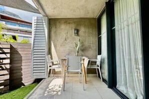 Ein Balkon mit Tisch und Stühlen, einem Blumentopf und Blick auf ein Gebäude.