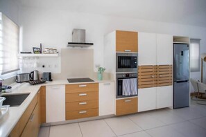 A modern kitchen with a microwave, oven, and refrigerator. - Luxurious Seafront Apartment with Pools (Grande Riviere Noire)