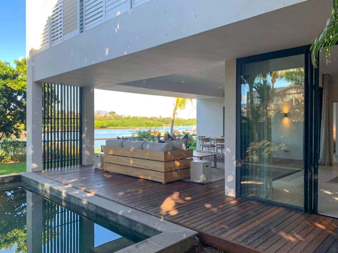A modern outdoor deck with a wooden floor, a built-in seating area, and a view of a body of water.