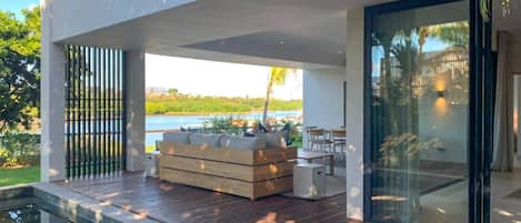 A modern outdoor deck with a wooden floor, a built-in seating area, and a view of a body of water.