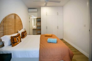Ein Schlafzimmer mit einem Bett, einem Nachttisch, einem Kleiderschrank und einem Spiegel.