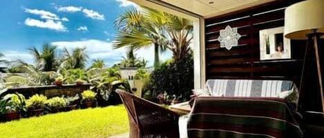 A room with a view of a lush garden, a bed with a striped blanket, and a chair.