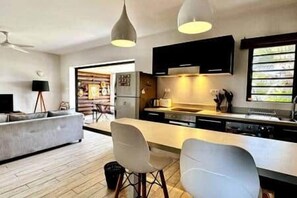 A modern kitchen with a central island, bar stools, and pendant lighting. - 2-bedroom apartment in Tamarin, shared pool and parking (Tamarin)