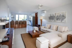 A modern living room with a sofa, coffee table, and dining area with chairs. - West Island CW9 · Sunrise Three Bed Apart in Marin (Grande Riviere Noire)