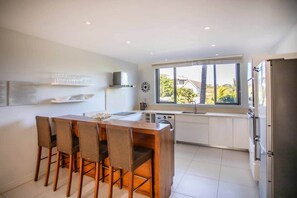 A modern kitchen with a dining area, large windows, and a view of the outdoors. - West Island CW9 · Sunrise Three Bed Apart in Marin (Grande Riviere Noire)