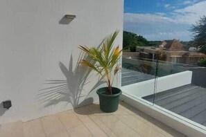 A potted plant on a balcony with a clear view of the sky and distant buildings. - Townhouse with 3 suites and private pool (Tamarin)