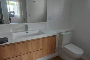 A bathroom with a white sink, wooden vanity, and a toilet. - Townhouse with 3 suites and private pool (Tamarin)