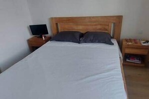 A bed with a wooden headboard, a bedside table with a lamp, and a small shelf with items. - Townhouse with 3 suites and private pool (Tamarin)