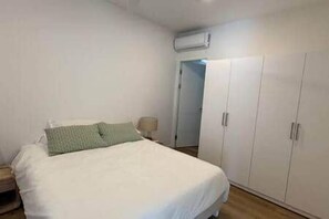 Une chambre à coucher comprenant un lit, une armoire et une porte donnant sur une autre pièce.