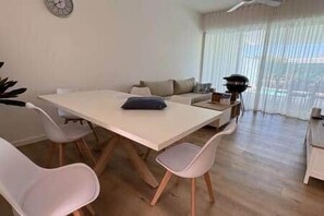 A dining area with a table and chairs, a sofa, and a view through sheer curtains. - 3-bedroom townhouse in Tamarin with private pool (Tamarin)