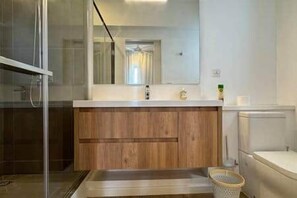 A bathroom with a wooden vanity, a mirror, a sink, and a shower area. - 3-bedroom townhouse in Tamarin with private pool (Tamarin)
