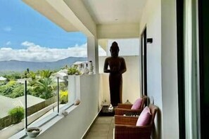 A balcony with a statue, wicker furniture, and a view of the landscape. - Penthouse with Panoramic Sea Views (Tamarin)