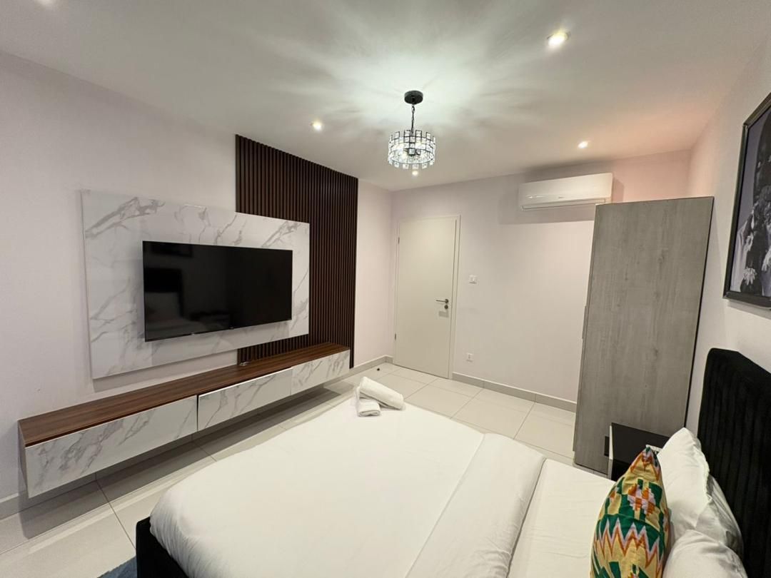 Habitación de hotel moderna con una cama grande, un televisor de pantalla plana en la pared, una lámpara de techo y un armario.