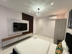 Habitación de hotel moderna con una cama grande, un televisor de pantalla plana en la pared, una lámpara de techo y un armario.