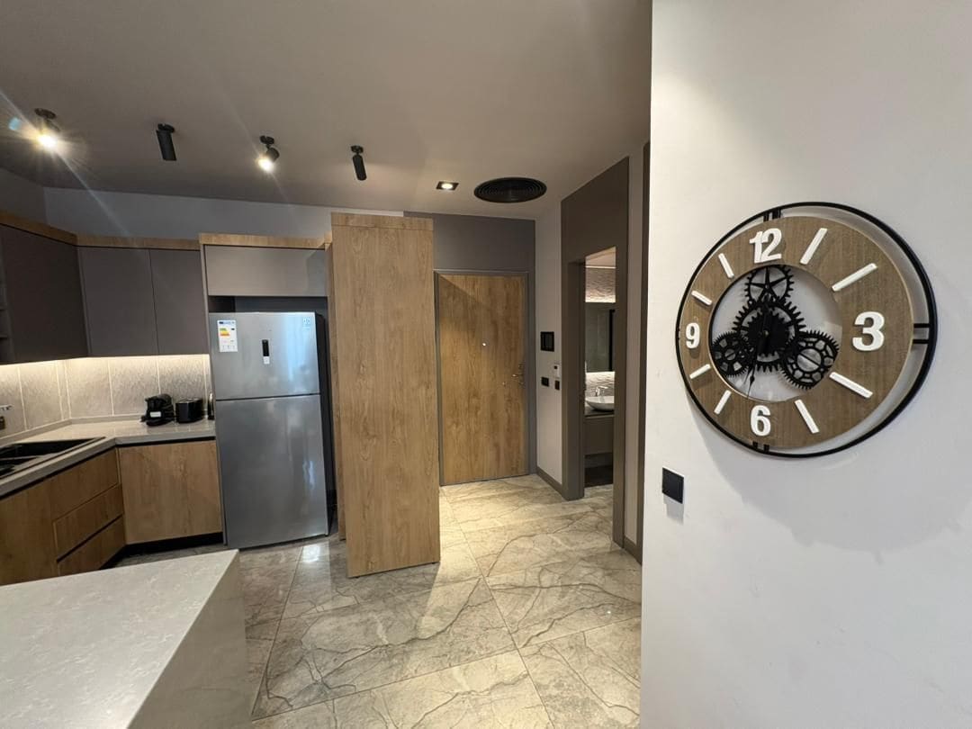 Una cocina moderna con refrigerador integrado, armarios de madera y piso de mármol.
