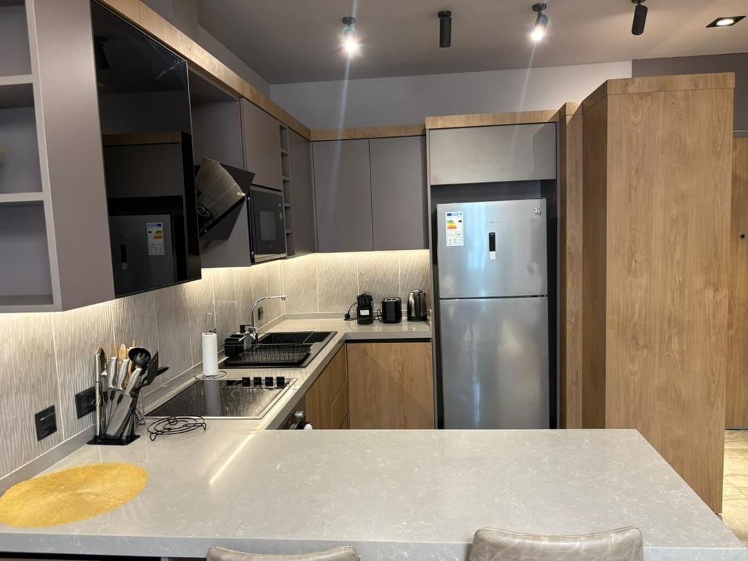 A modern kitchen with a stainless steel refrigerator, a built-in oven, and a granite countertop.