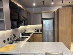 Una cocina moderna con un refrigerador de acero inoxidable, un horno empotrado y una encimera de granito.