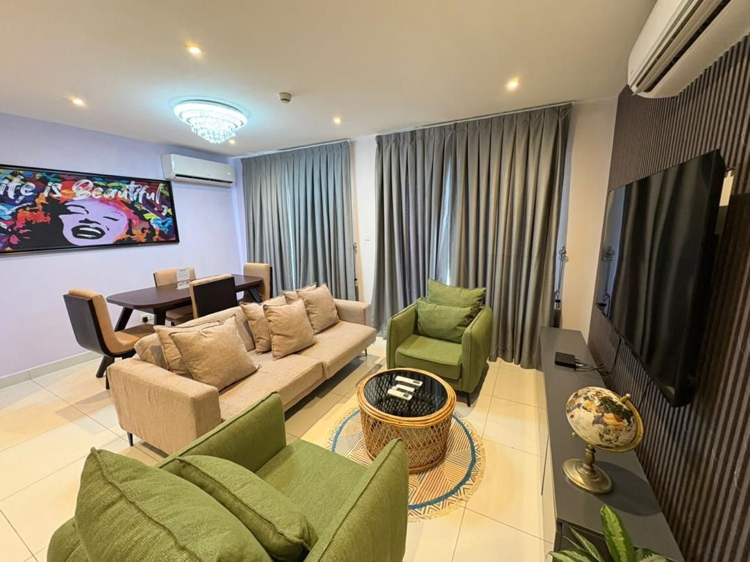 Una sala de estar moderna con un sofá, sillones, una mesa de centro y un televisor de pantalla plana.