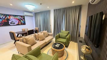 Una sala de estar moderna con un sofá, sillones, una mesa de centro y un televisor de pantalla plana.