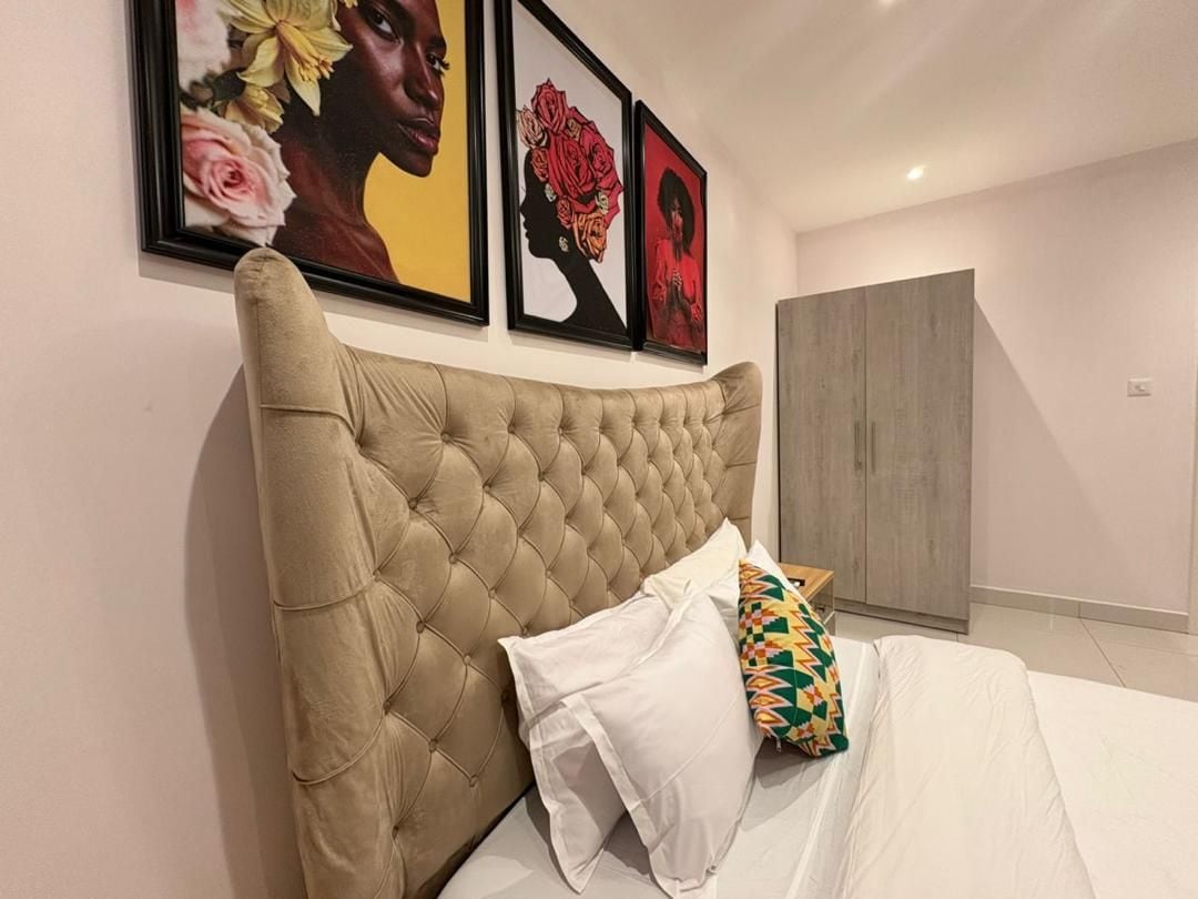 A bedroom with a tufted headboard, a bed with white bedding, and a colorful pillow.