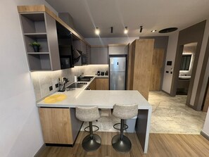 Una cocina moderna con una isla central, taburetes de bar y estanterías empotradas.