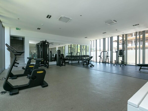 Un gimnasio con máquinas de cardio, pesas libres y mancuernas.