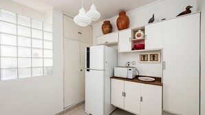 Une cuisine de taille réduite, avec un réfrigérateur blanc, un four à micro-ondes et un plan de travail en bois.