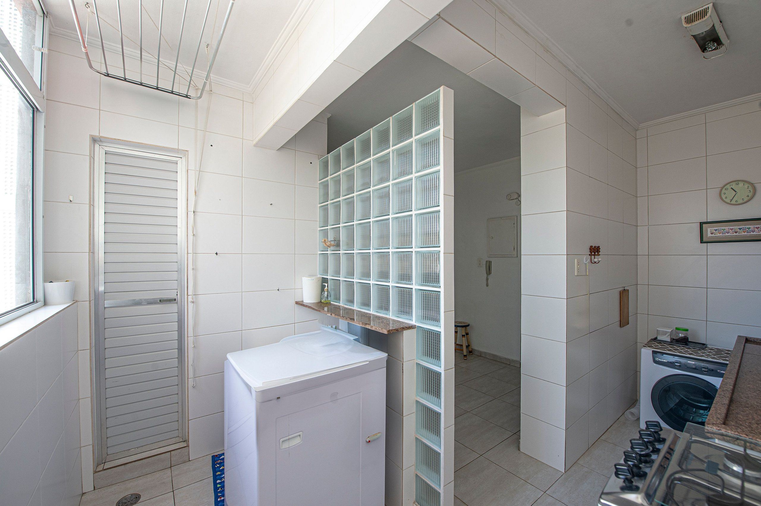 Un espace dédié à la lessive, comprenant un lave-linge, un étendoir et un petit tabouret.