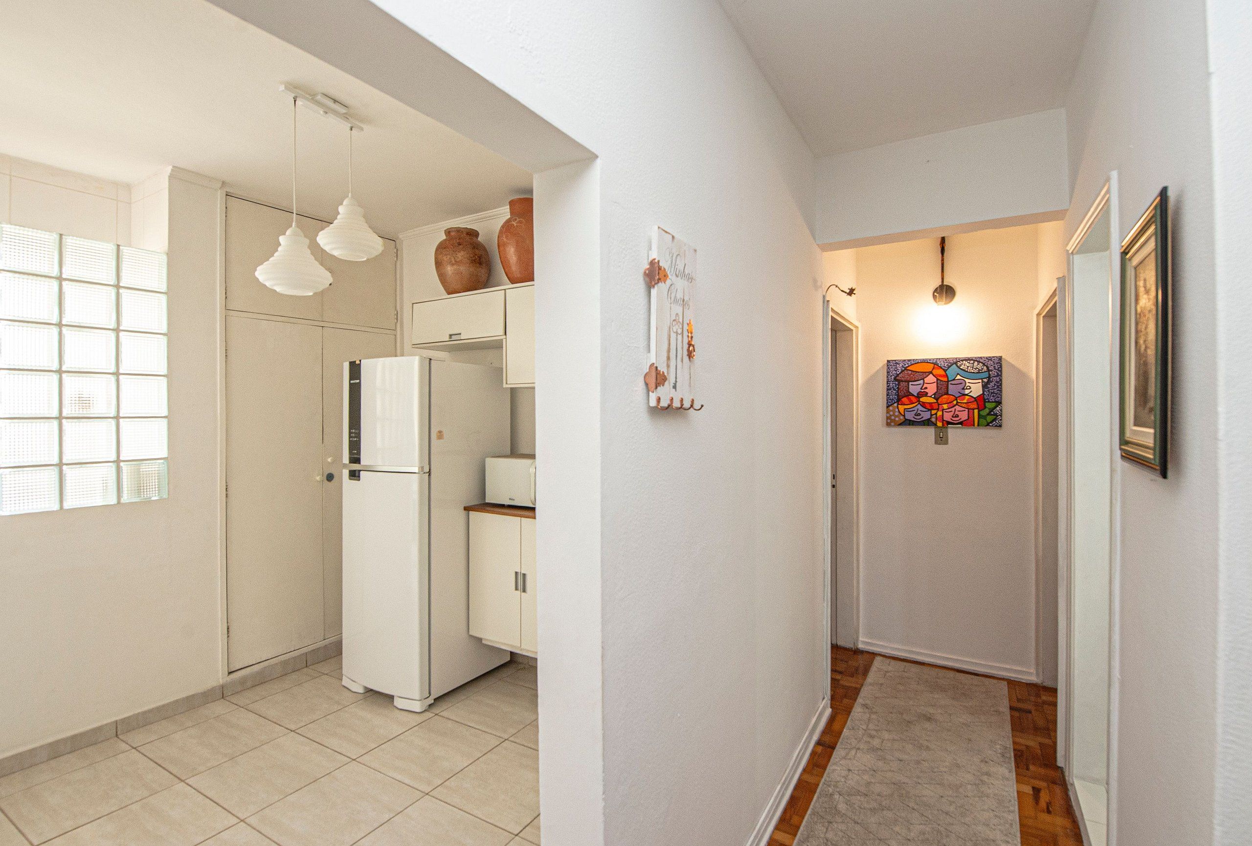 A kitchen with a refrigerator, cabinets, and hanging light fixtures.