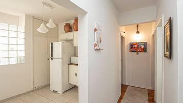A kitchen with a refrigerator, cabinets, and hanging light fixtures.